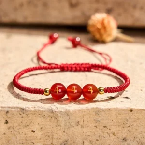 Angel Number 444 Red Agate Bracelet with engraved beads and gold spacers on stone surface