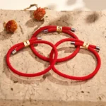 Angel numbers red string bracelets collection flat lay with dried flowers and stone texture