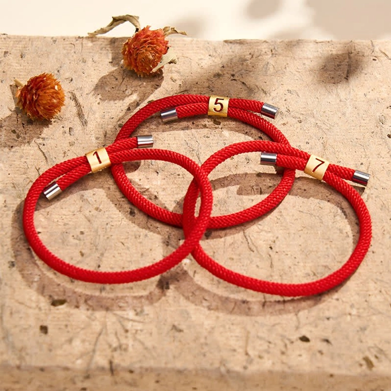 Angel numbers red string bracelets collection flat lay with dried flowers and stone texture