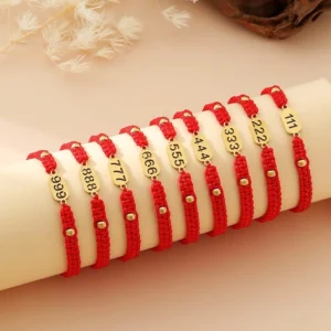 Angel numbers red black braided string bracelets collection with gold lucky number tags displayed on cylindrical stand