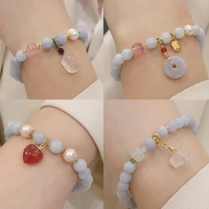 Aquamarine chalcedony charm bracelet with light blue beads and teardrop pendant on wrist, worn with white shirt