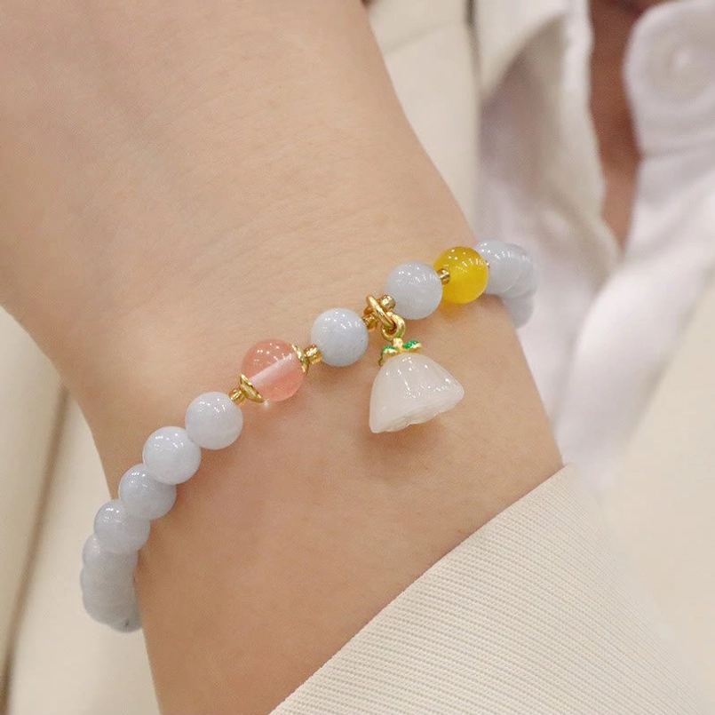 Aquamarine lotus pod charm bracelet with pink quartz, yellow accent and lotus pendant on wrist