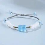 Aquamarine Pixiu Hetian white jade healing bracelet with adjustable knot on light blue background