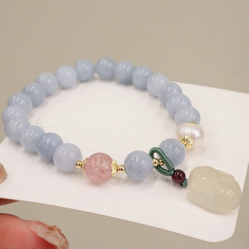 Red bead aquamarine charm bracelet with freshwater pearl and gold findings on wrist