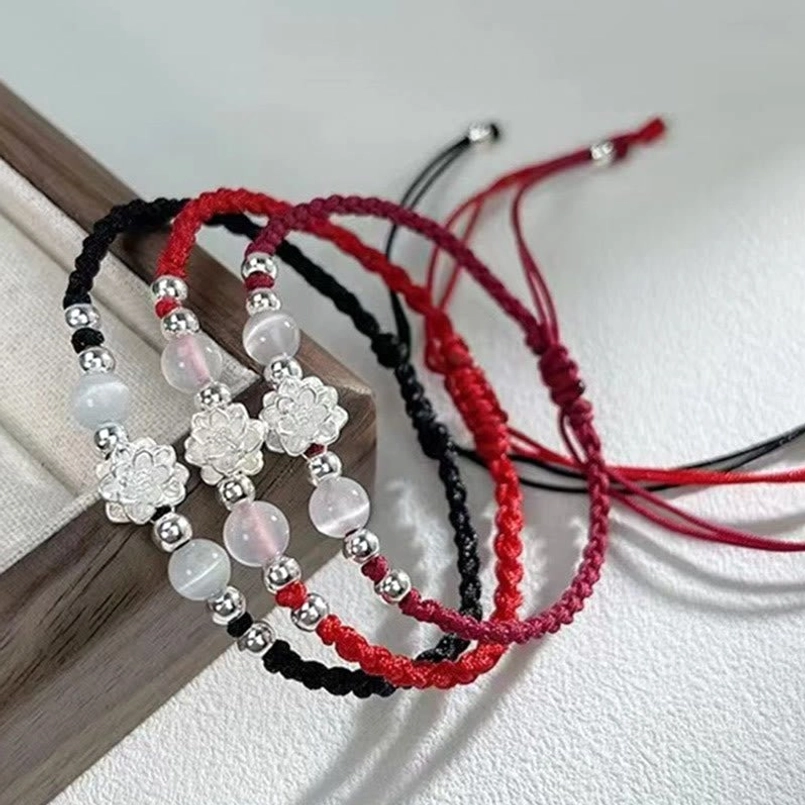 assorted braided protection red string bracelets with silver lotus charms flat lay