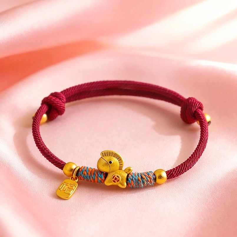auspicious zodiac horse red string bracelet flat lay on pink silk fabric background