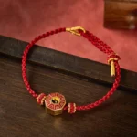 Bagua red string bracelet with gold charm on wooden surface - protection feng shui