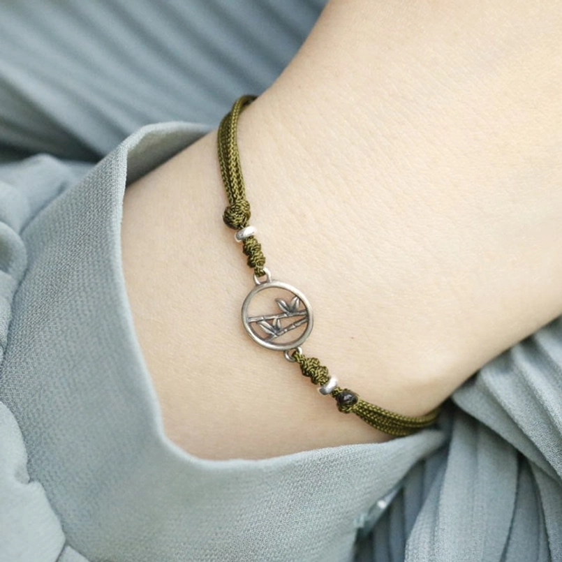 Detailed wrist view showing woven red cord texture and charm placement on adjustable bracelet