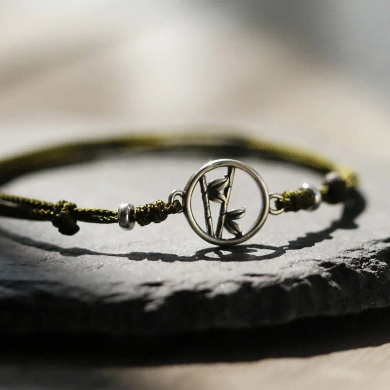 Close-up detail of bamboo charm and knot on 925 silver red string bracelet