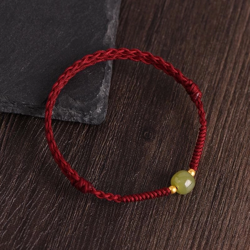 Single barrel jade gold bead bracelet with dark red cord close-up