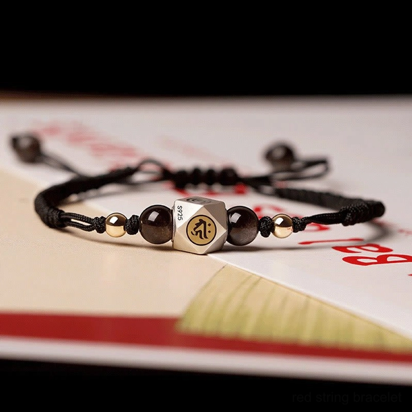 Black woven faith bracelet with dark round beads and engraved silver center bead detail