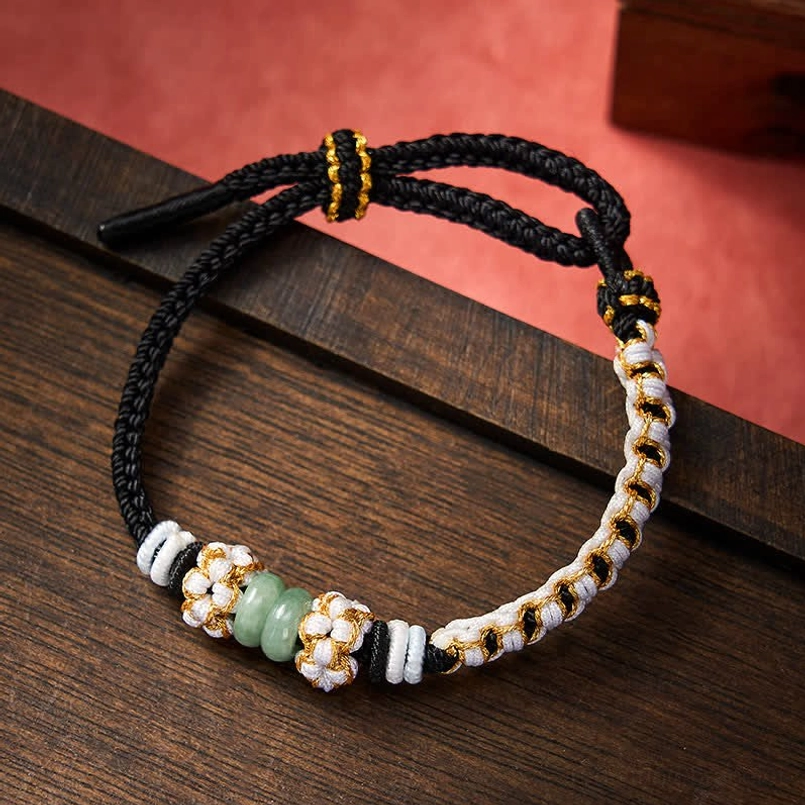 Black Chinese knot bracelet with jade beads and metal accents on dark wooden surface