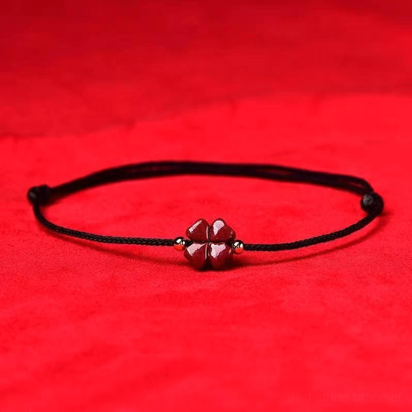Black cinnabar four leaf clover string bracelet with matching charm flat lay