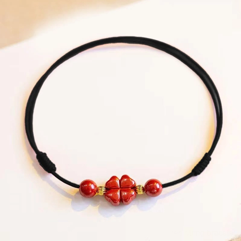Black cord cinnabar four leaf clover anklet with red lucky charm and round beads flat lay