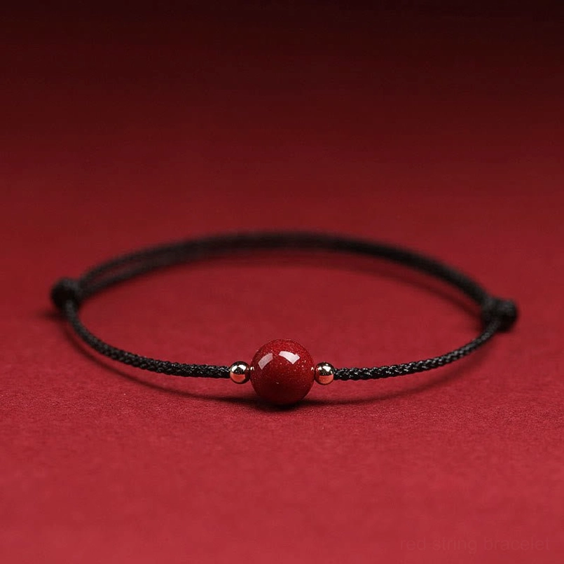 Single cinnabar bead black string bracelet with metal beads on solid red background