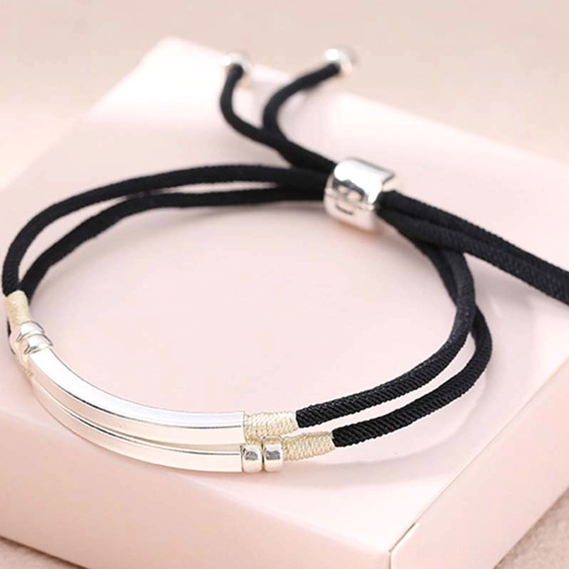 Black braided cord with polished sterling silver hardware on neutral matte background detail shot