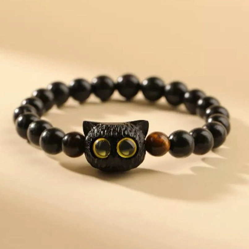 Black ebony cat head red string bracelet front view on beige background