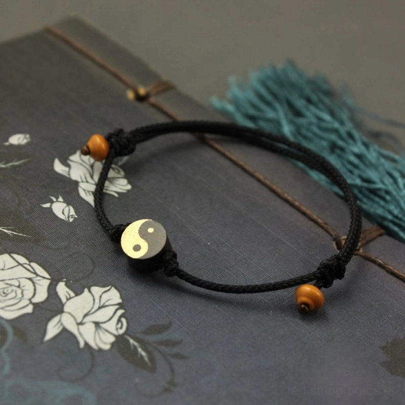 Black Ebony Yin Yang string bracelet on dark decorative fabric