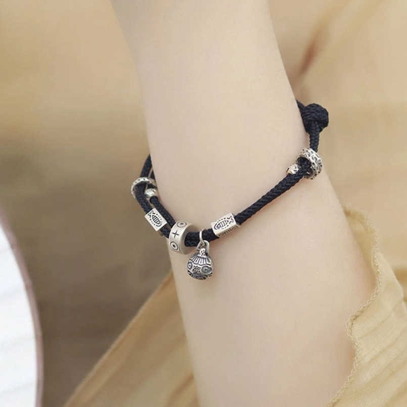 Black braided fortune bracelet with silver bell charm worn daily
