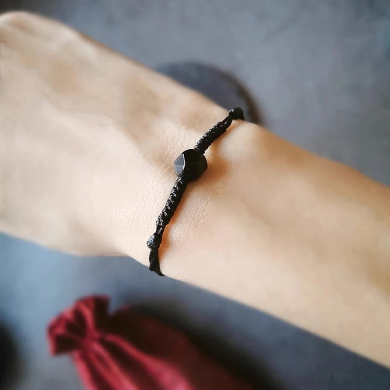Black obsidian braided bracelet worn on forearm with faceted central bead