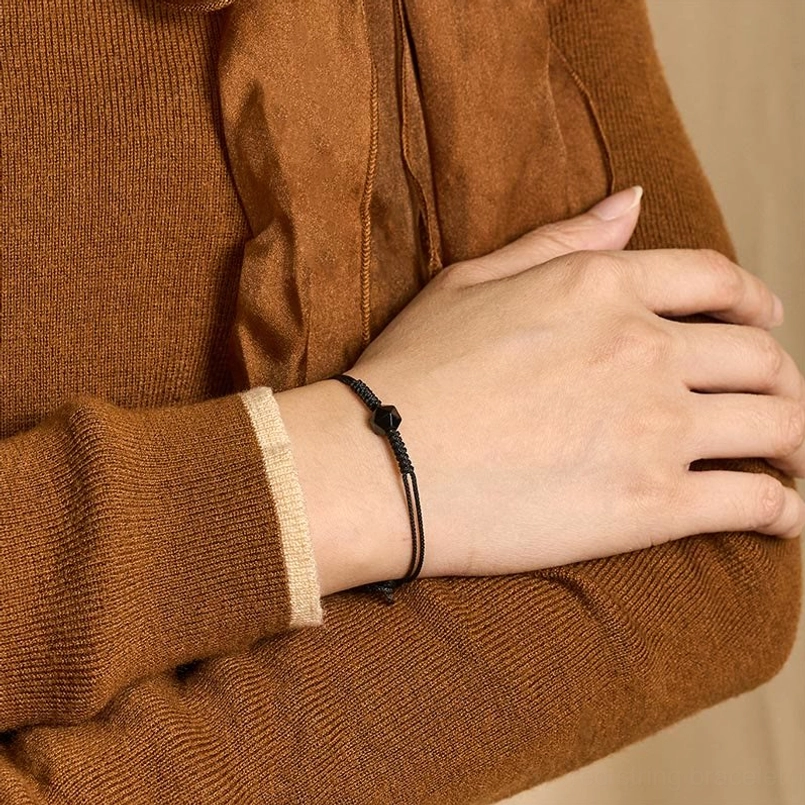Black obsidian strength bracelet worn on wrist with brown knitted sweater close-up