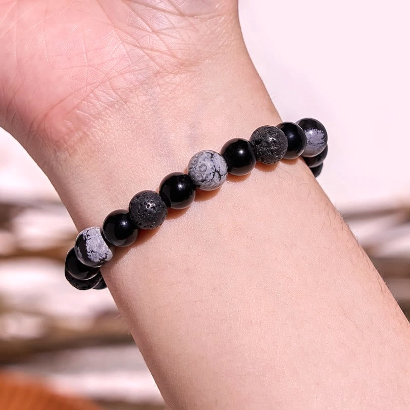 Man wearing black obsidian lava rock yin yang strength bracelet on wrist, close-up view