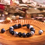 Black obsidian and lava rock yin yang bracelet with white stone accents displayed on wooden tray