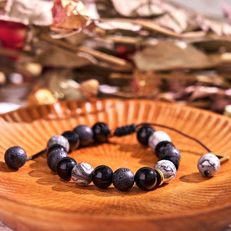 Black obsidian and lava rock yin yang bracelet with white stone accents displayed on wooden tray