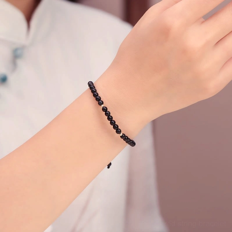 Black obsidian beaded bracelet worn on wrist, side view with adjustable cord tail