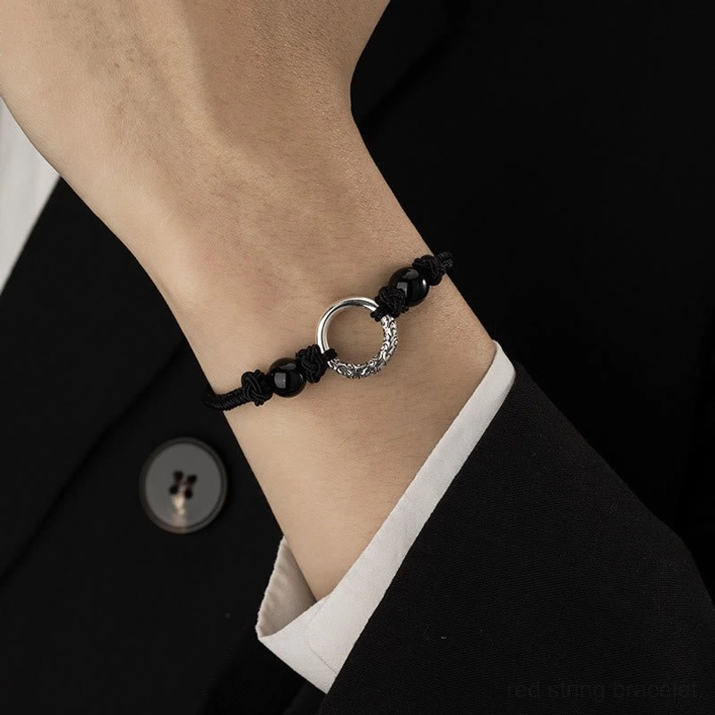 Close up of worn peace buckle bracelet paired with formal black suit