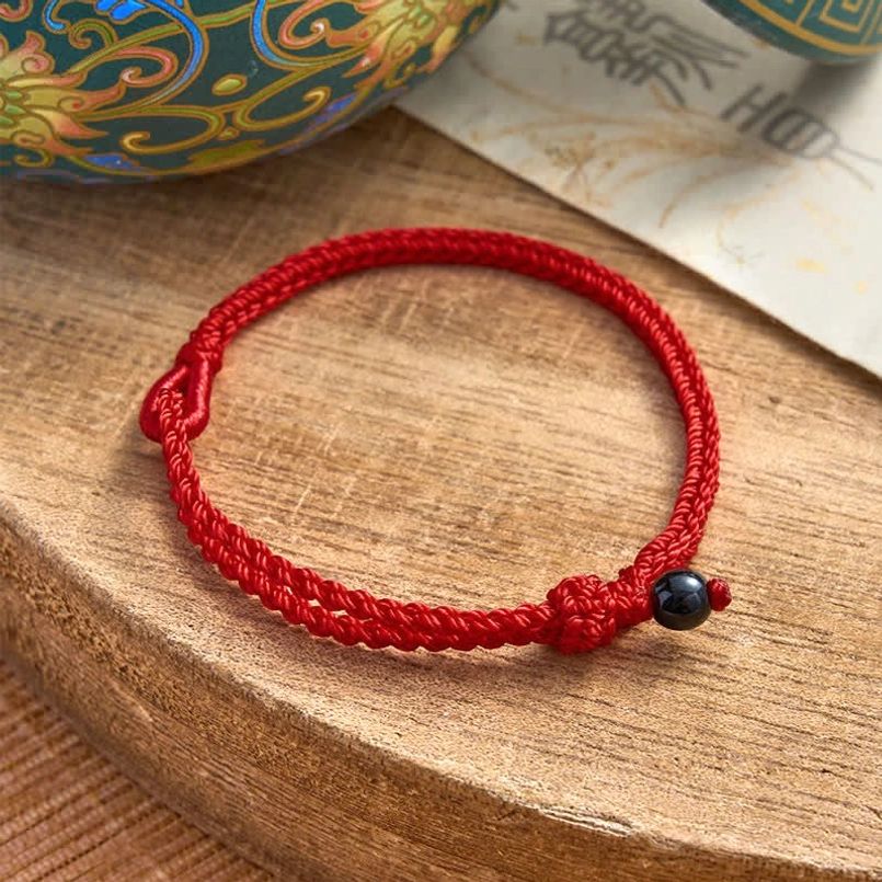 Black onyx red string balance bracelet worn on wrist with protection symbolism
