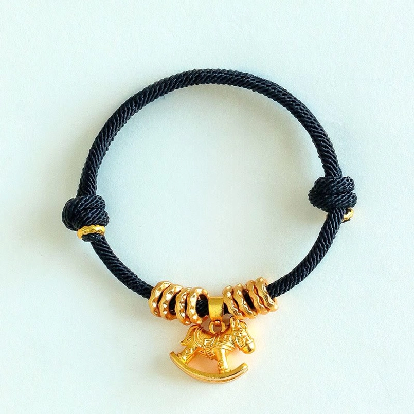 Black woven string horse charm protection bracelet top view on matte white background
