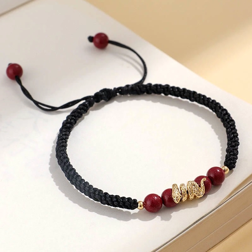 Flat lay top view of black rope Year of Snake cinnabar braided bracelet