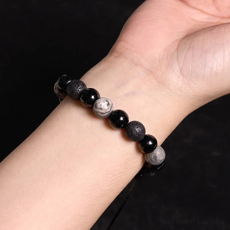 Minimalist black obsidian and lava rock beaded bracelet worn on male wrist, side view