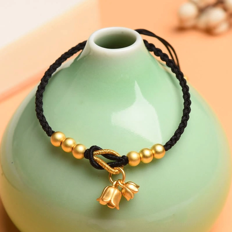Black woven bracelet with lily pendant showing twisted rope knot and gold beads