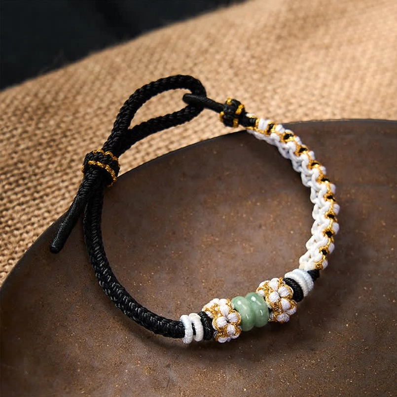 Black knot bracelet with jade beads displayed on burlap fabric and ceramic tray