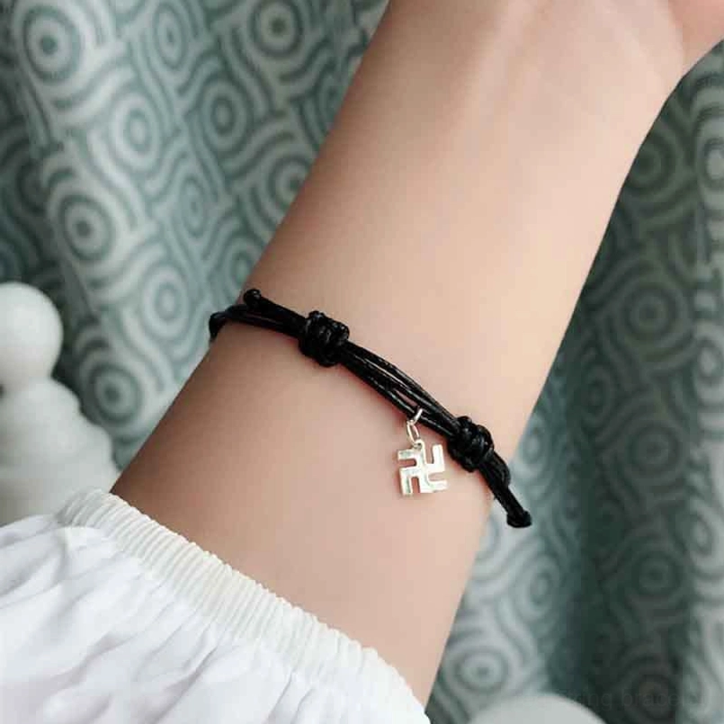 Black braided luck bracelet with hanging swastika charm and woven cord detail