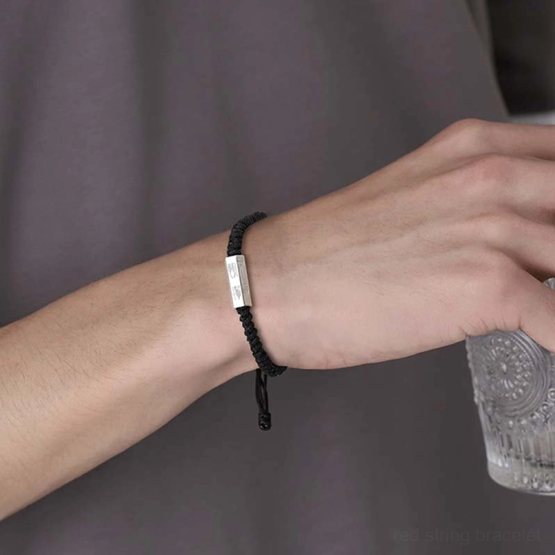 Slim black cord silver engraved charm bracelet close up on casual wrist