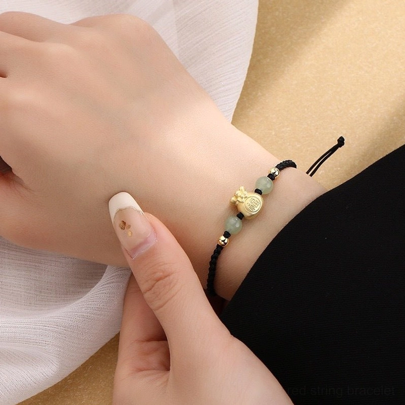 Black woven cord lucky bracelet on wrist with adjustable sliding knot and jade beads