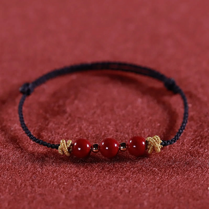 Black braided cinnabar bracelet front flat view with golden woven knots