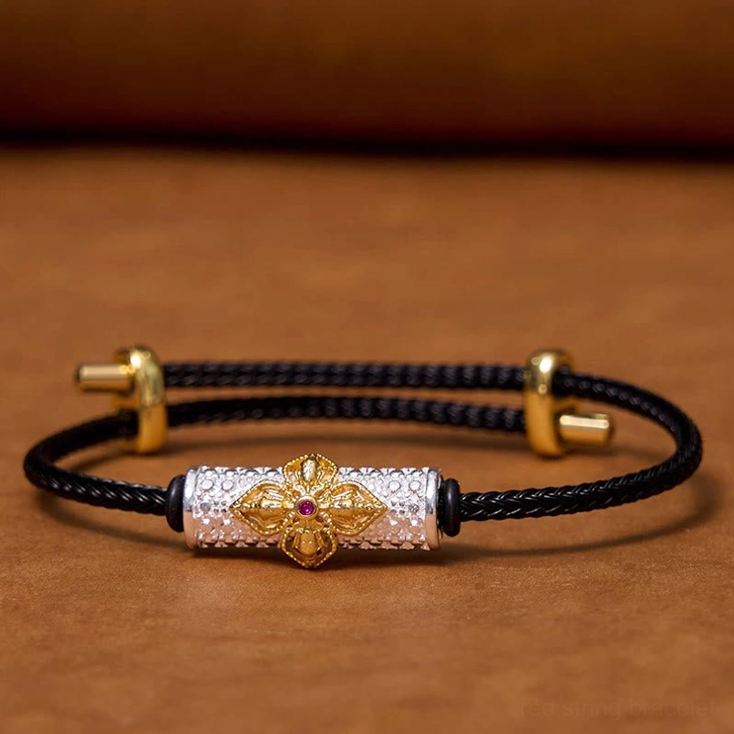 Black string protection bracelet with copper flower charm and precious metal accents