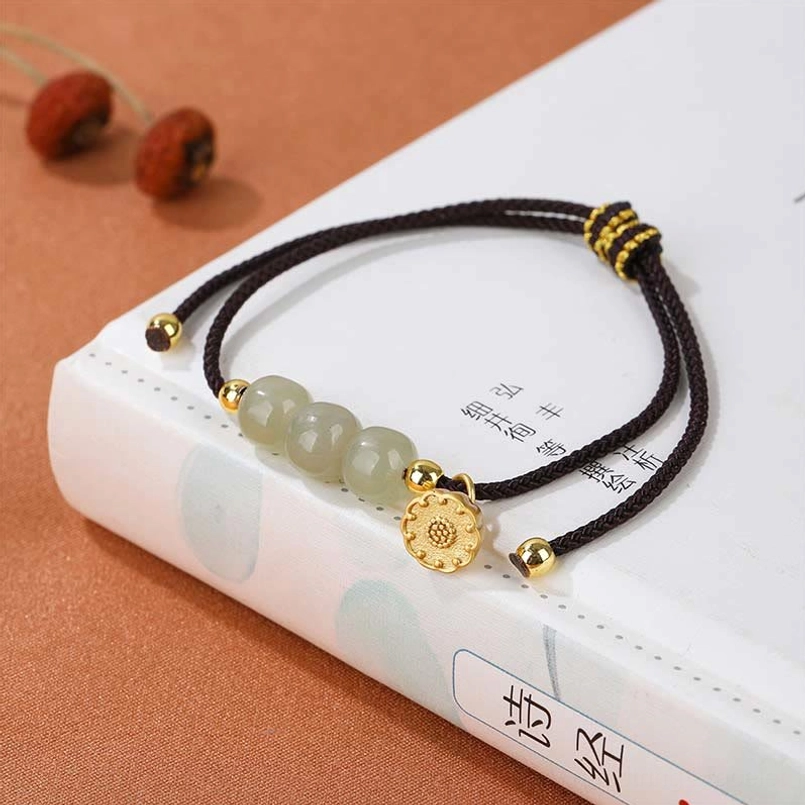 Black braided string Hetian jade lotus pod bracelet placed on vintage poetry book