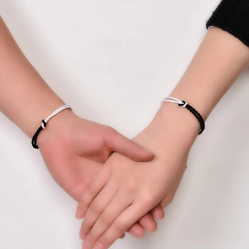 Couple wearing matching slim black and white braided healing bracelets metal detail