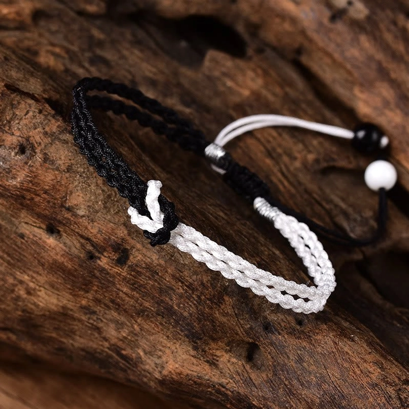 Close-up black white color-block braided bracelet with decorative beads and adjustable cord