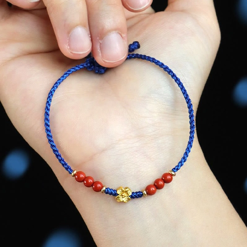Blue braided beaded bracelet with red agate beads copper clover pendant close up on dark bokeh background