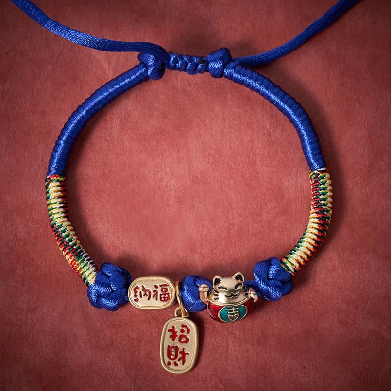 Blue handmade pet collar with multicolor woven sections and fortune charms flat lay