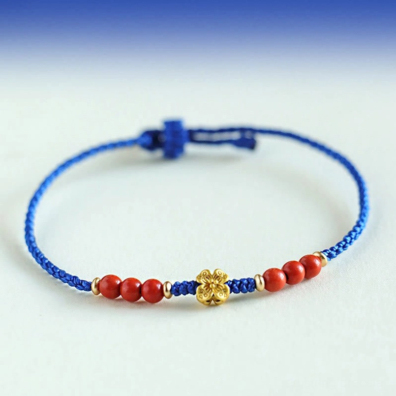Blue string beaded bracelet with south red agate beads copper clover charm flat lay on gradient blue background