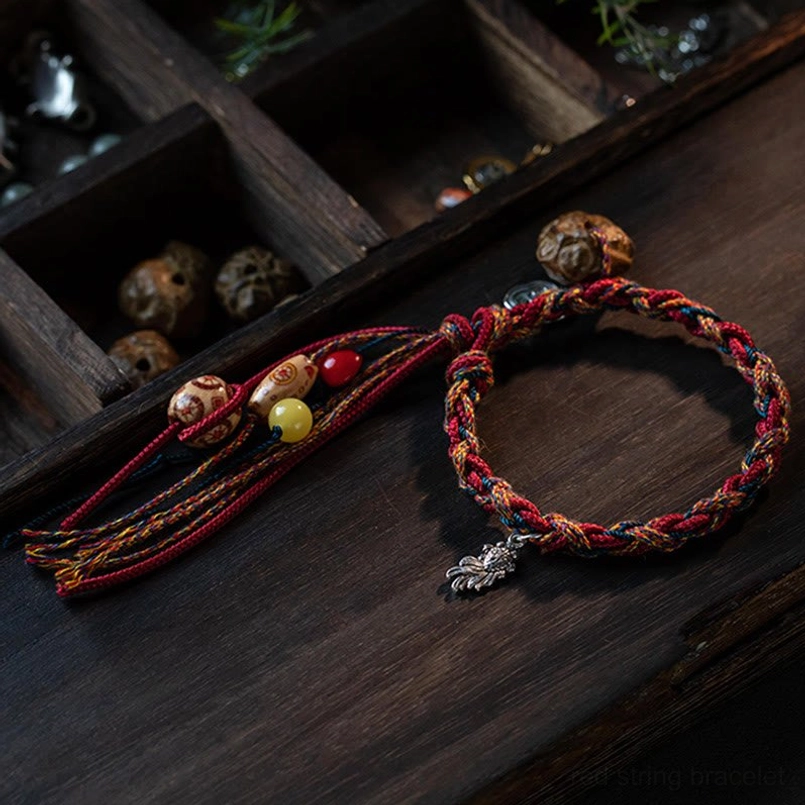Boho woven friendship bracelet with multicolor braided rope and silver leaf charm on wooden surface