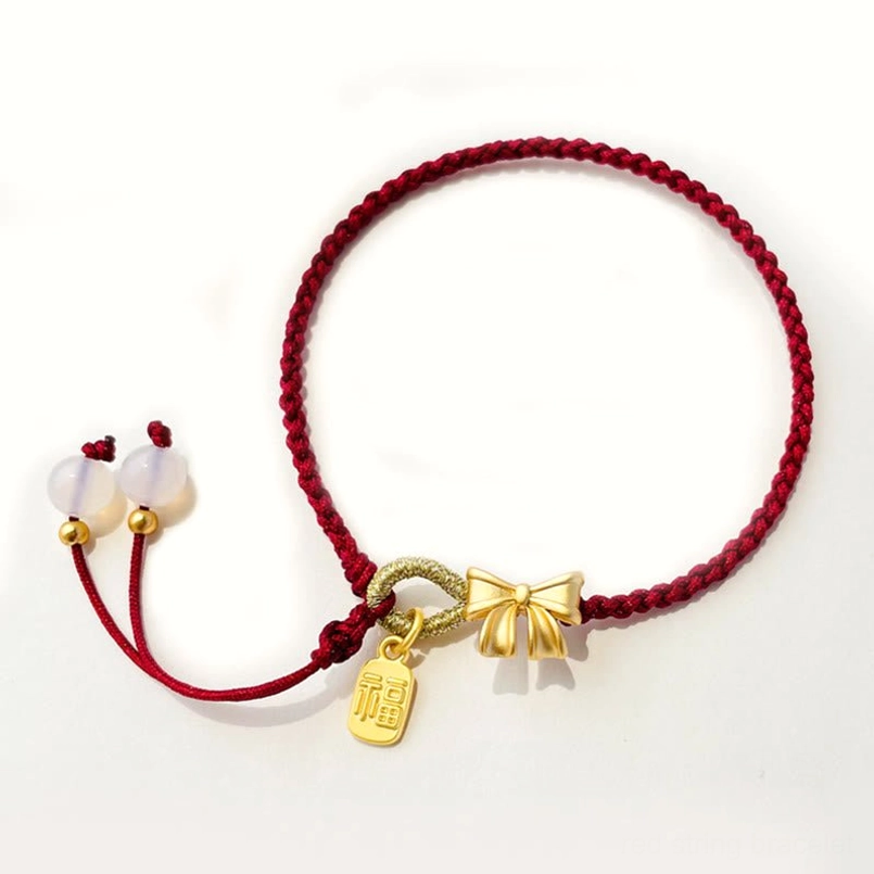 Bow knot red string bracelet with gold charm, Fu tag, and white bead adjustable tassel on white background