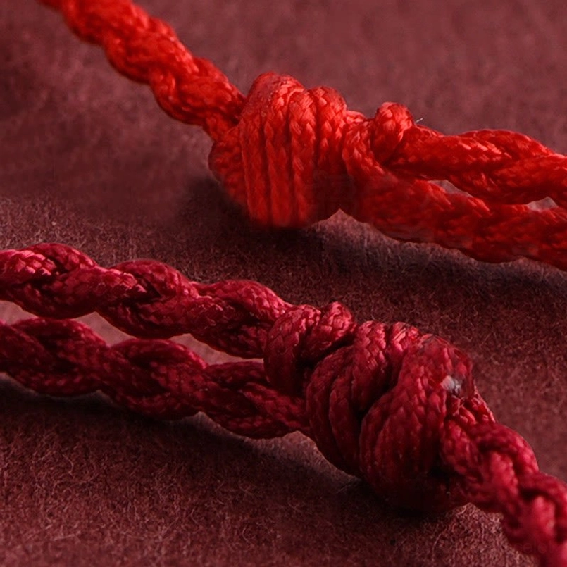 Angled close-up of bracelet decorative knot and thick braided red rope construction
